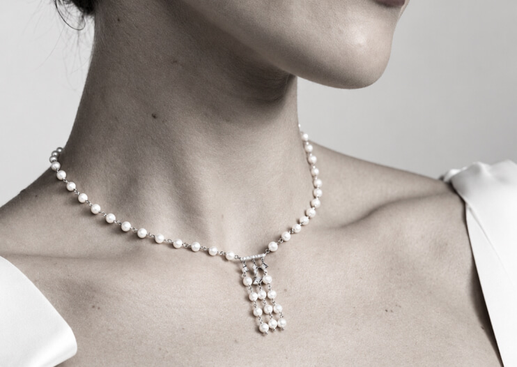 IMPERIAL Pearl black-and-white photo of a woman wearing a pearl necklace with hanging strands of pearls